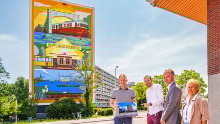 Wethouder Postma, kunstenaar Michiel Meulemans en bestuurder Ruud van Nieuwaal staan voor de mooi beschilderde kopgevel van de Marrewijkflat